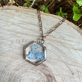 Forget-me-not flower preserved in resin and set in a copper pendant necklace