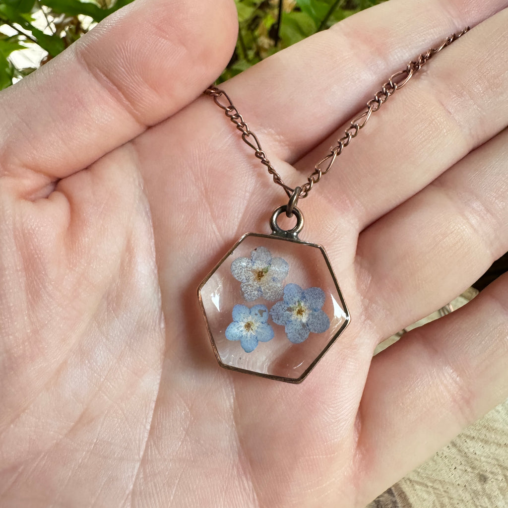 Forget-me-not flower preserved in resin and set in a copper pendant necklace