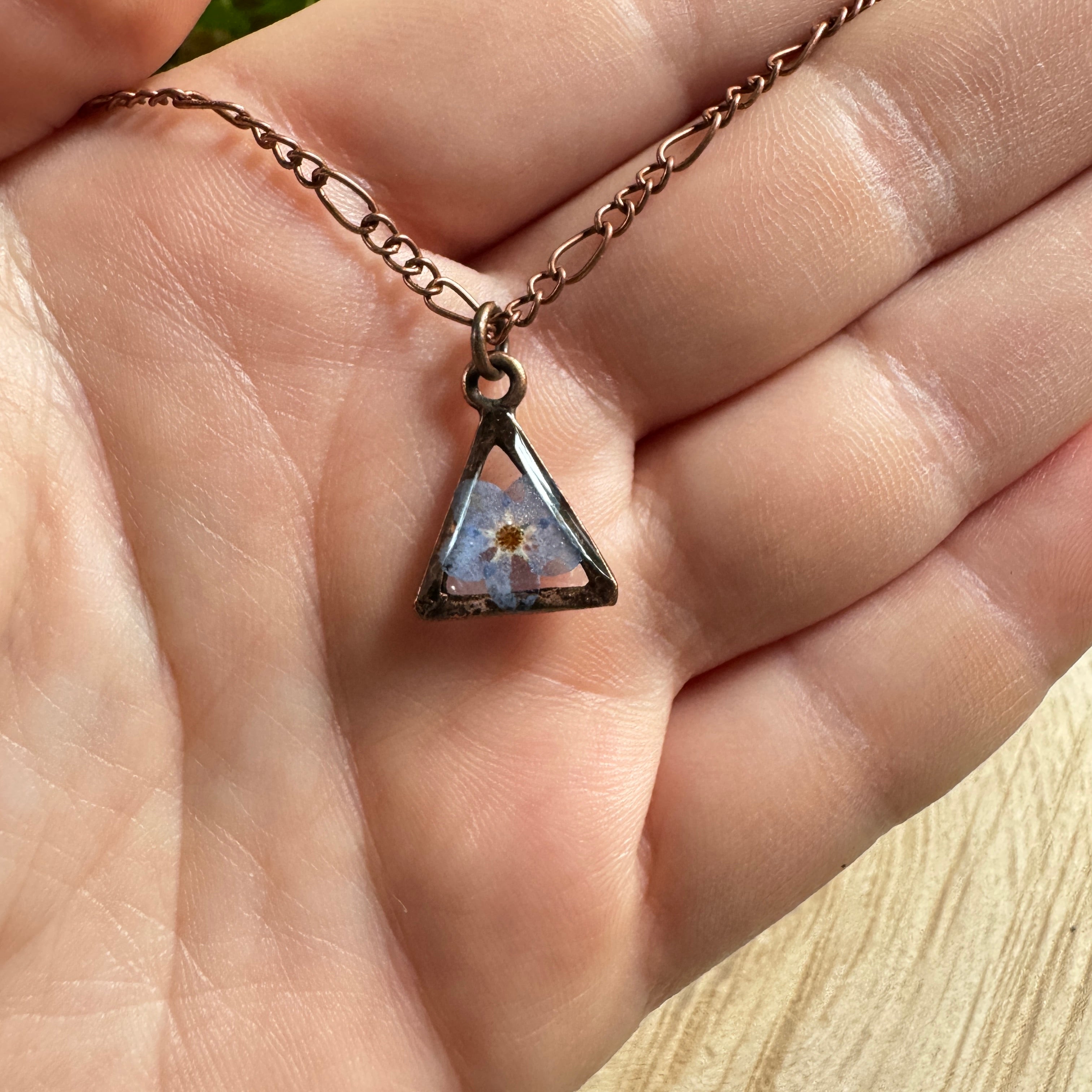 Forget-me-not flower preserved in resin and set in a copper pendant necklace