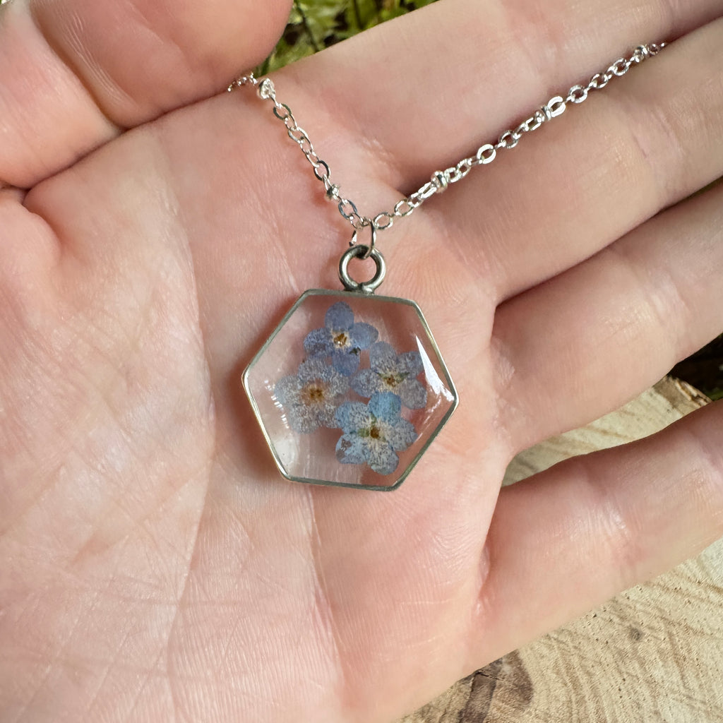 Forget-me-not flower preserved in resin and set in a silver pendant necklace